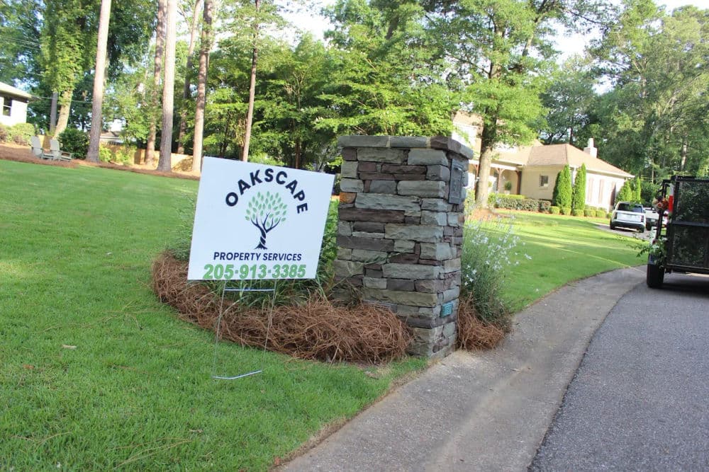 OAKSCAPE Property Services sign near a landscaped residential area, showcasing professional landscaping.